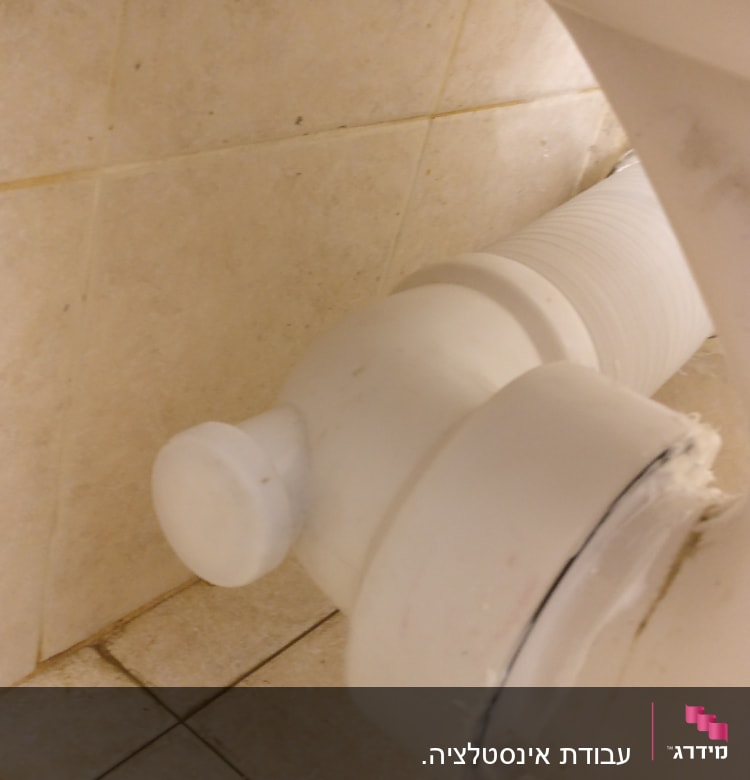 צינור ביוב לבן מחובר לקיר קרמיקה